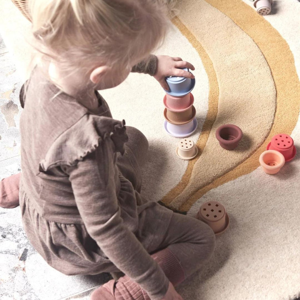 Petite fille jouant avec une tour empilable de toutes les couleurs en silicone