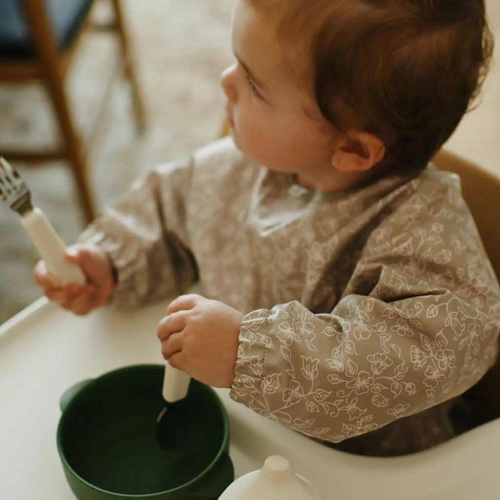 Bébé sur sa chaise haute avec les essentiels pour manger Minika