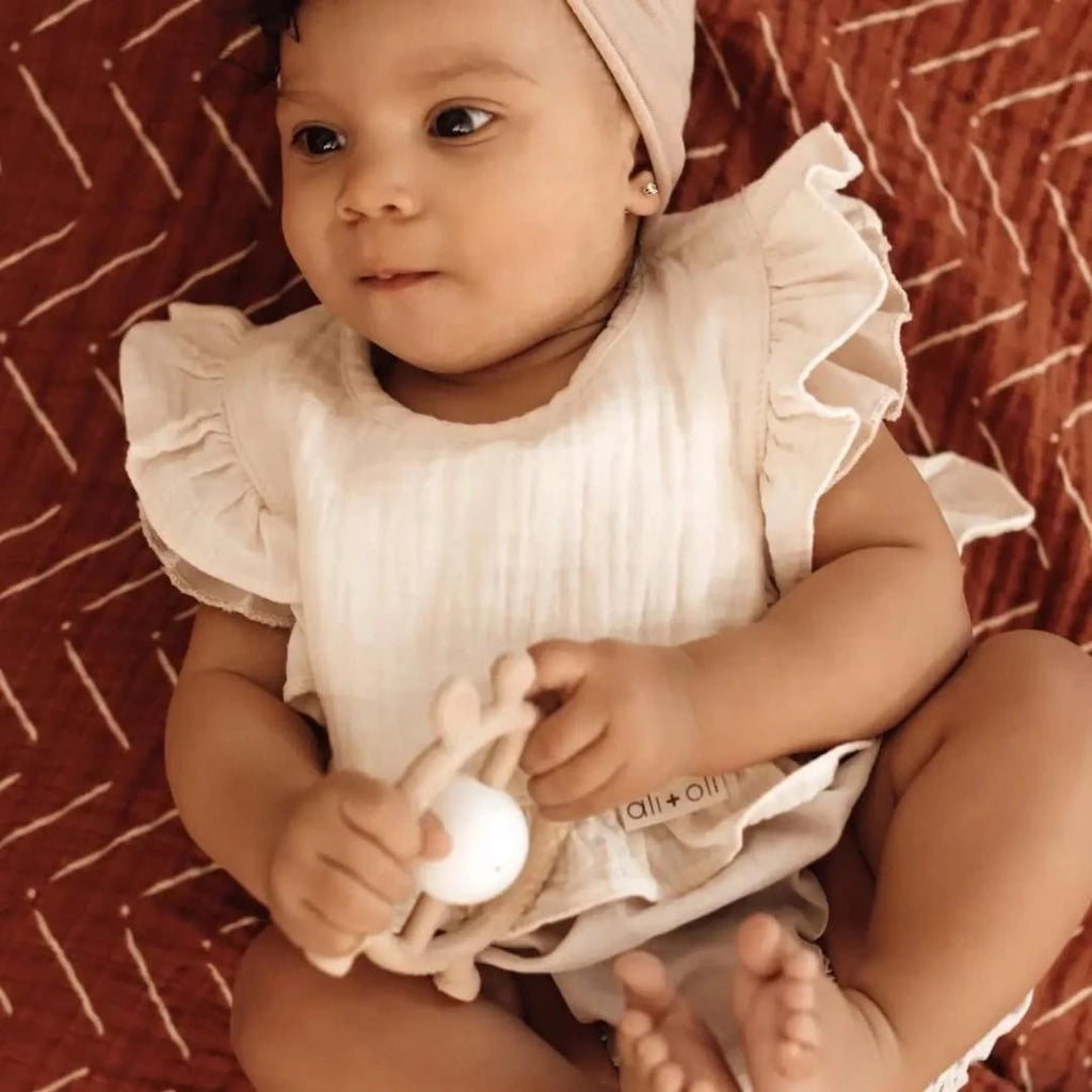 Un bébé portant un bavoir en mousseline de coton Ali+Oli.