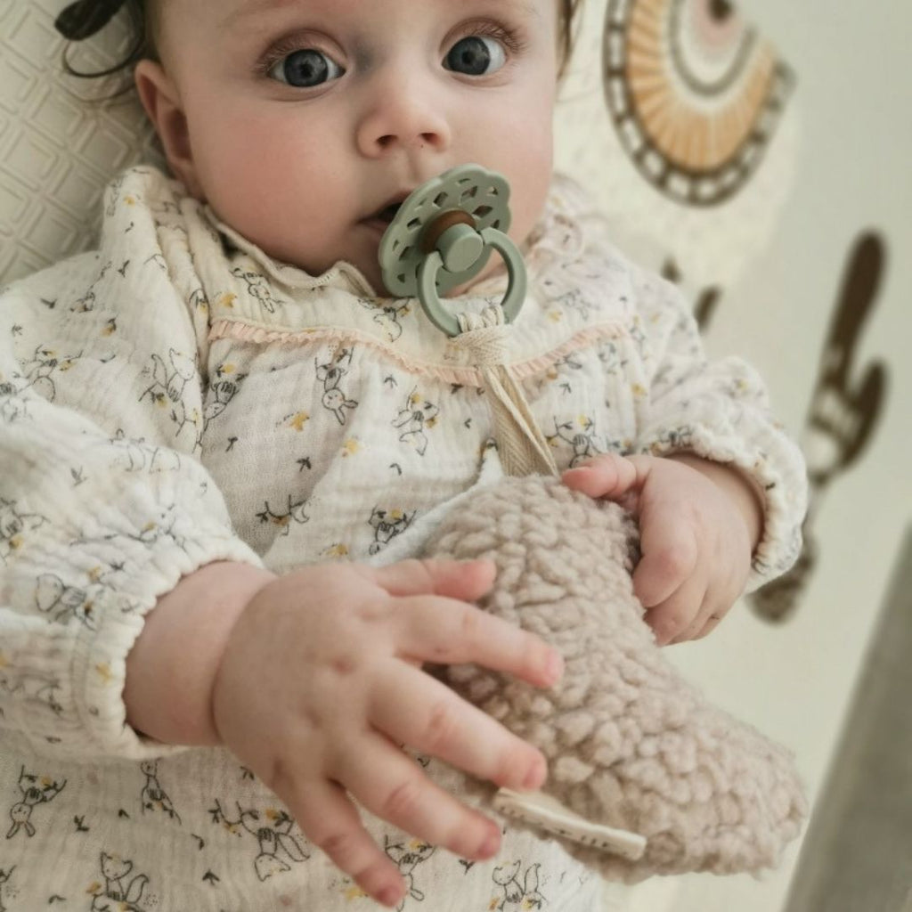 Un bébé avec son porte tétine en peluche Moon de chez Ali+oli.