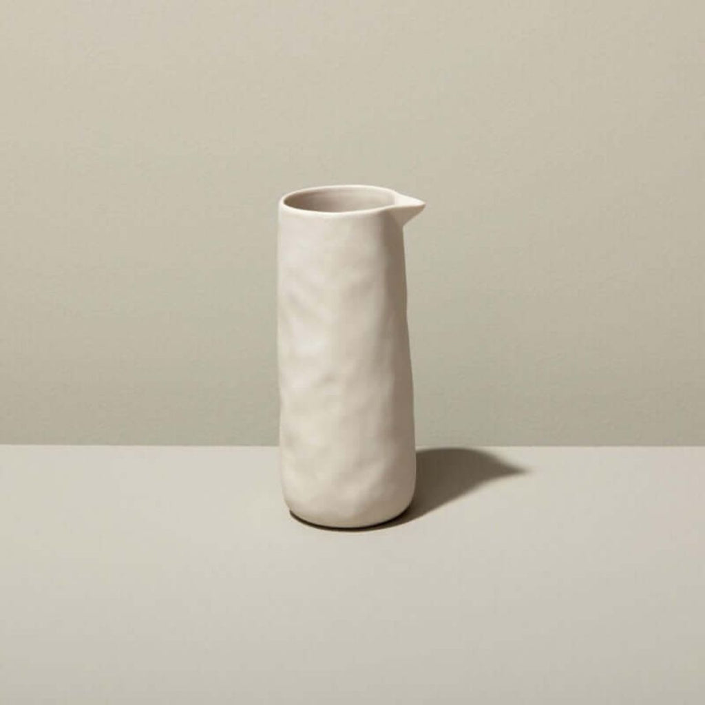 Un pot à service BeHome en grès de couleur gris, présenté sur un fond blanc. Le pot, d'une forme simple et épurée, présente une surface lisse et mate. Parfait pour servir le lait également