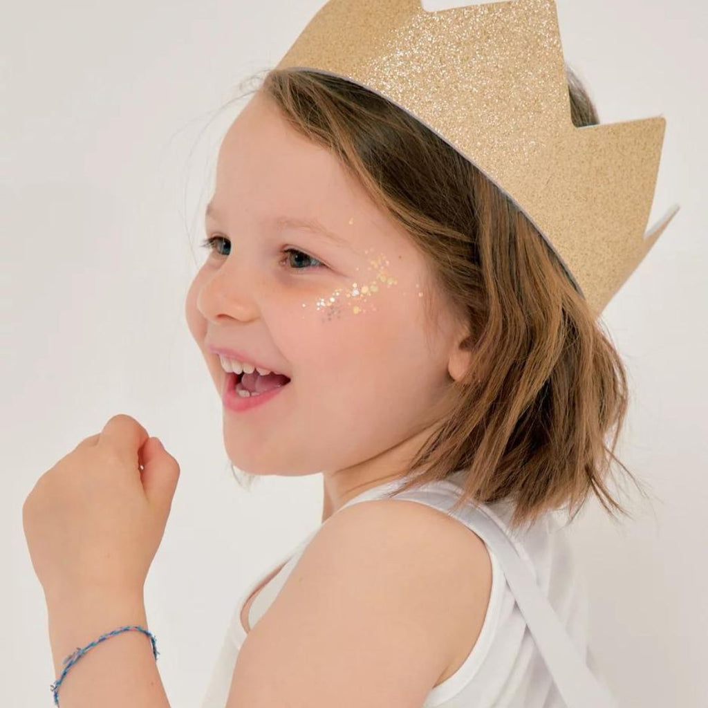 Une petite fille souriante porte la Couronne Ratatam Kids. La couronne est scintillante et colorée, et la petite fille a l'air heureuse et princesse.
