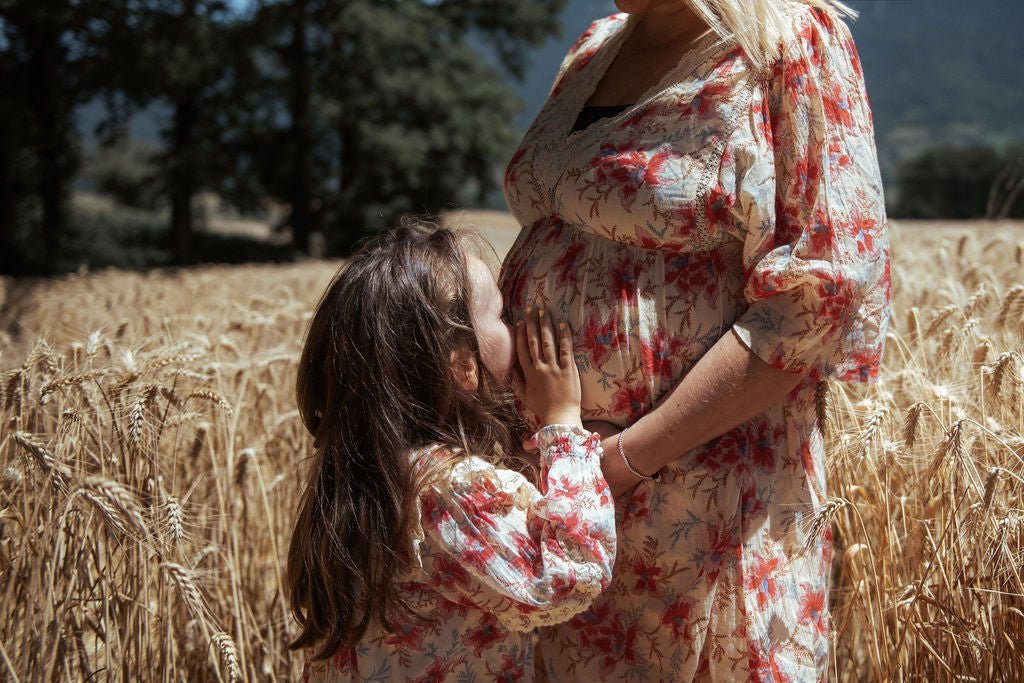 Photo d'une femme enceinte avec sa petite fille dans un champs de blés portant toutes les deux la robe OTTI pour la mère et ARINOLA pour la fille de chez LOUISE MISHA